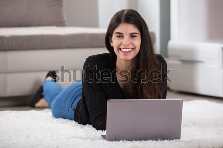 Young Woman Lying On Rug Using Laptop Stock photo © AndreyPopov