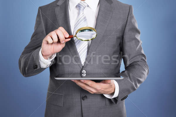 Auditor holding magnifying glass and tablet Stock photo © AndreyPopov