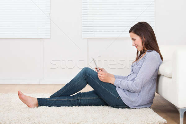 Woman Using Tablet Pc While Sitting On Rug Stock photo © AndreyPopov