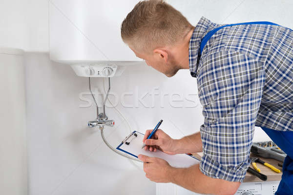 Plumber With Clipboard In Front Of Electric Boiler Stock photo © AndreyPopov