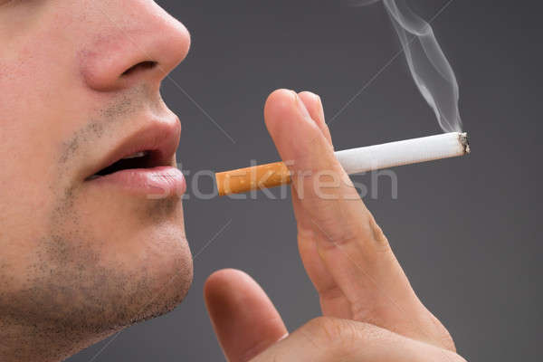 Stock photo: Man Smoking Against Gray Background