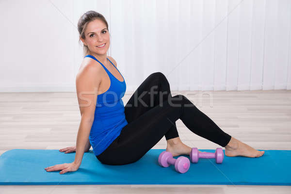 Woman With Dumbbell Sitting On Exercise Mat Stock photo © AndreyPopov