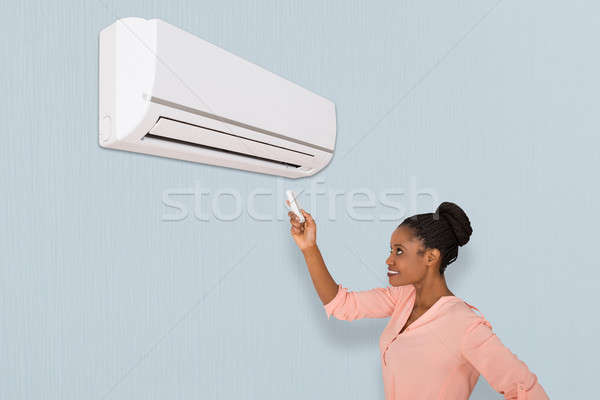 Woman Operating Air Conditioner Stock photo © AndreyPopov