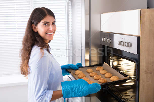 Woman Taking Out Tray Of Baked Cookies From Oven Stock photo © AndreyPopov