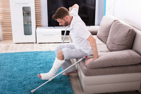 Man With Broken Leg Getting Up From Sofa Stock photo © AndreyPopov