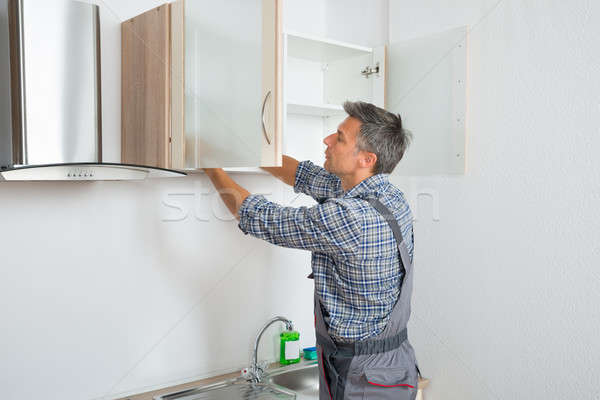 Serviceman Fixing Cabinet With Screwdriver In Kitchen Stock photo © AndreyPopov