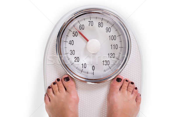 Woman's Legs On Weighing Scale Over White Background Stock photo © AndreyPopov