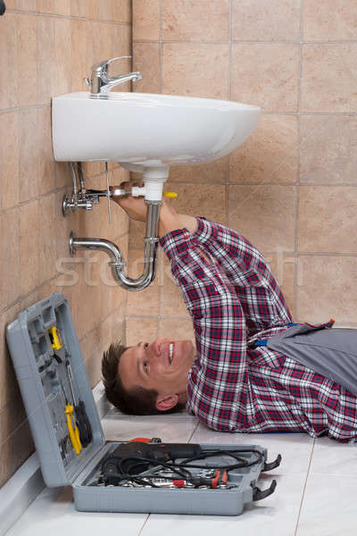 Plumber Lying On Floor Fixing Sink Stock photo © AndreyPopov