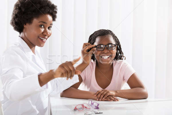 Stock photo: Smiling Girl Wearing Eyeglasses In Front Of Optometrist