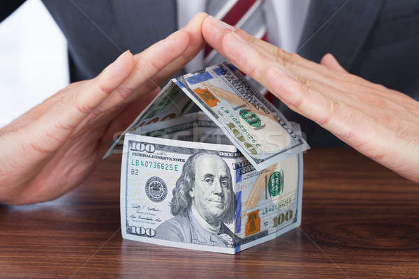 Stock photo: Businessman Sheltering House Made With Bank Notes