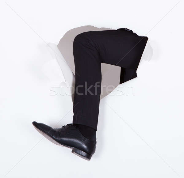 Businessman's Leg Breaking Through White Wall Stock photo © AndreyPopov