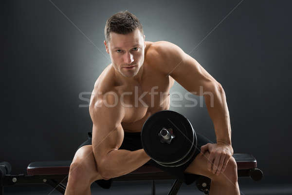 Muscular Man Exercising With Dumbbells On Chair Stock photo © AndreyPopov