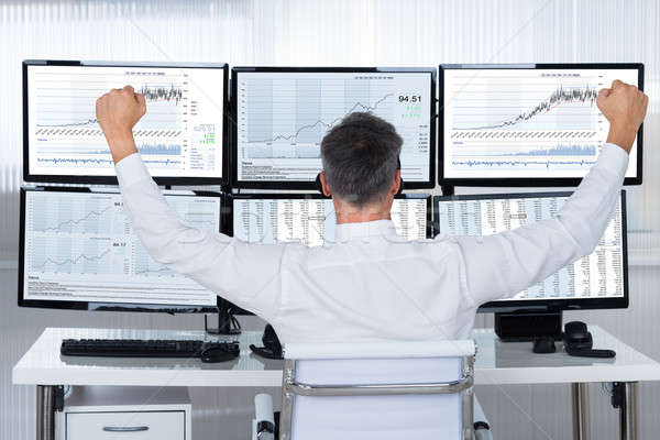 Successful Trader With Arms Raised Looking At Graphs On Screens Stock photo © AndreyPopov