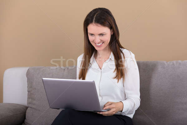 Woman Sitting On Sofa With Laptop On Lap Stock photo © AndreyPopov