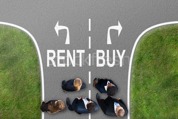 Stock photo: Businesspeople Standing On Street With Sign Showing Rent And Buy