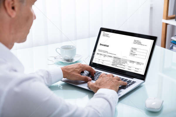 Businessman Looking At Invoice On Laptop Stock photo © AndreyPopov