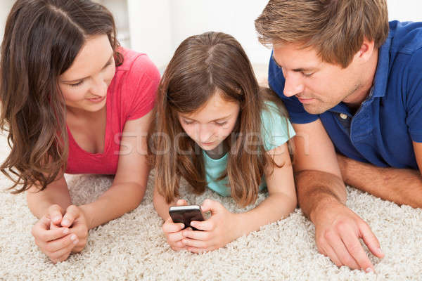 Parents Looking At Daughter Using Smart Phone Stock photo © AndreyPopov
