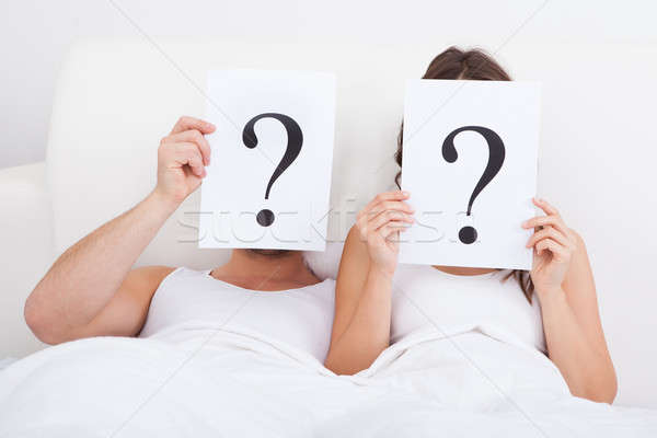 Couple Lying On Bed Holding Question Mark Stock photo © AndreyPopov