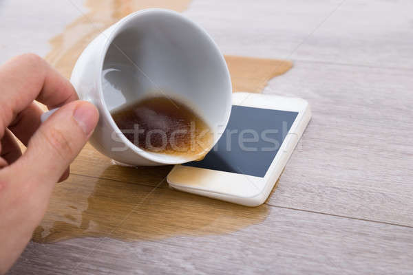Person's Hand Spilling Coffee On Cellphone Stock photo © AndreyPopov