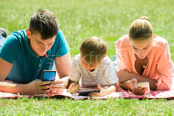 Family Laying Down In The Park With Their Smart Phones Stock photo © AndreyPopov