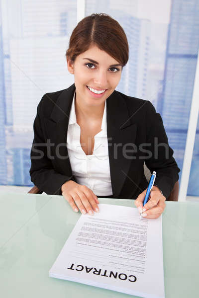 Smiling Businesswoman Signing Contract At Desk Stock photo © AndreyPopov