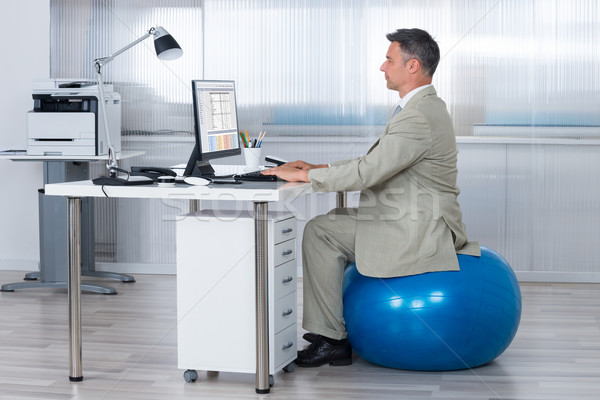 Businessman Using Computer While Sitting On Exercise Ball Stock photo © AndreyPopov