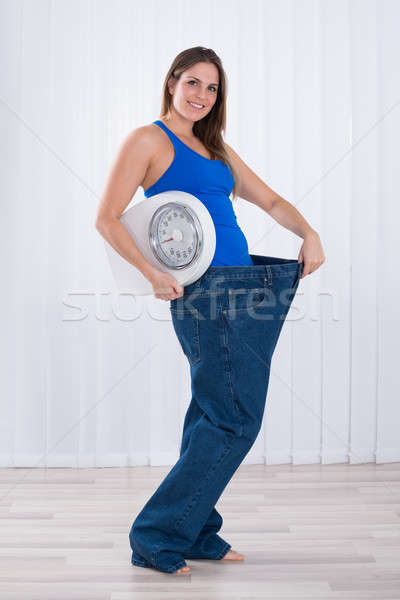 Woman With Weighing Machine Wearing Big Jeans Stock photo © AndreyPopov