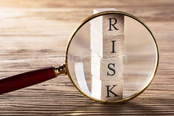 Stock photo: Person Placing Magnifying Glass Over Risk Block