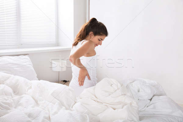 Frau Sitzung Bett Rückenschmerzen Hand Stock foto © AndreyPopov