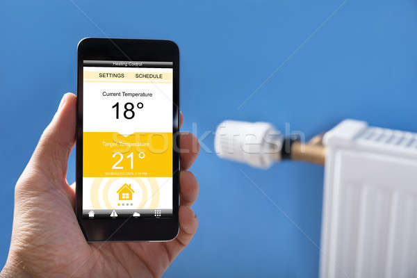 Person Hand Setting Temperature Of Thermostat Using Mobilephone Stock photo © AndreyPopov