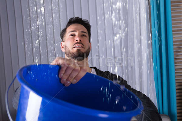 Man Holding Bucket While Water Leakage Stock photo © AndreyPopov