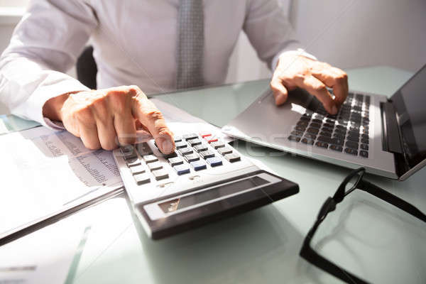 Businessman Using Laptop And Calculator Stock photo © AndreyPopov