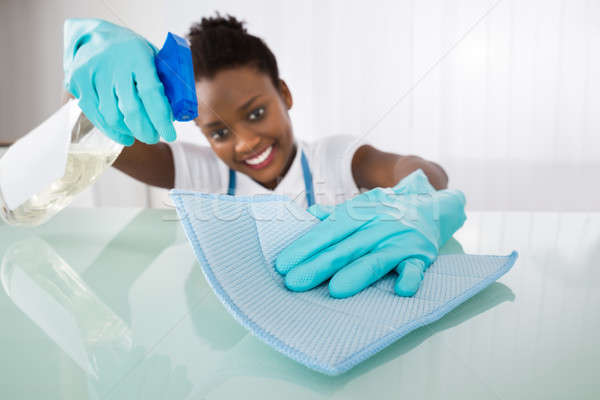 Happy Female Janitor Cleaning Desk With Rag Stock photo © AndreyPopov