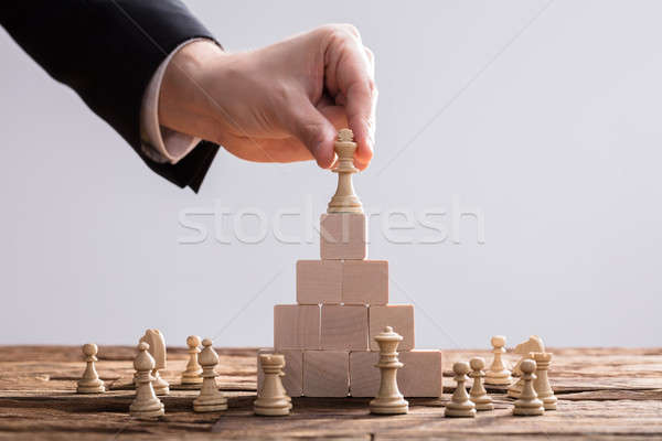 Businessperson Placing King Chess Piece On Top Of Wooden Blocks Stock photo © AndreyPopov