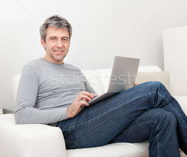 Altos hombre sesión sofá usando la computadora portátil casa Foto stock © AndreyPopov