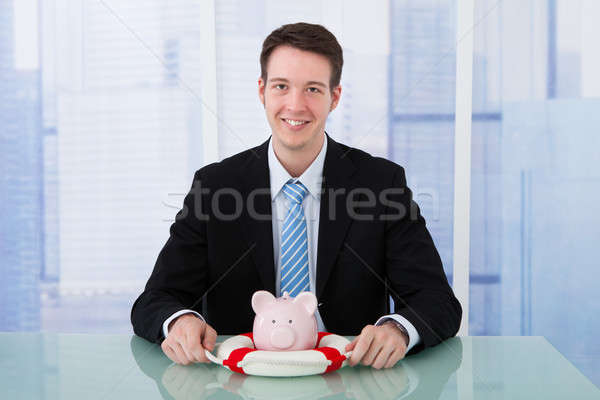 Businessman Protecting Piggybank With Lifebelt Stock photo © AndreyPopov