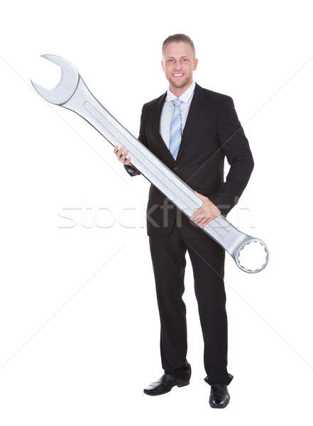 Businessman in a smart suit holding a large metal spanner Stock photo © AndreyPopov