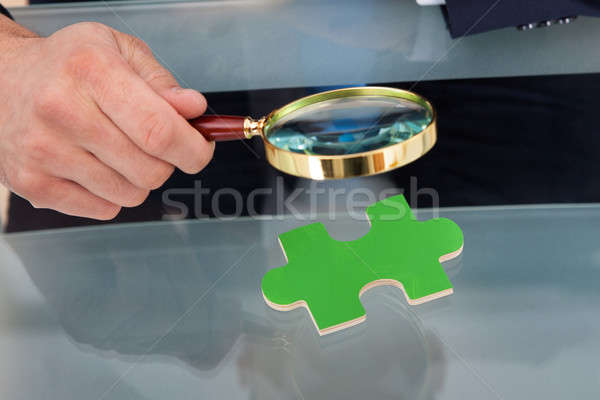 Businessman Scrutinizing Puzzle Piece With Magnifying Glass Stock photo © AndreyPopov