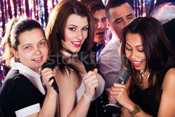 Friends Singing Into Microphones At Karaoke Party Stock photo © AndreyPopov