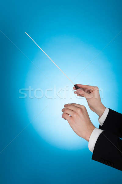 Musician Holding Baton Against Blue Background Stock photo © AndreyPopov