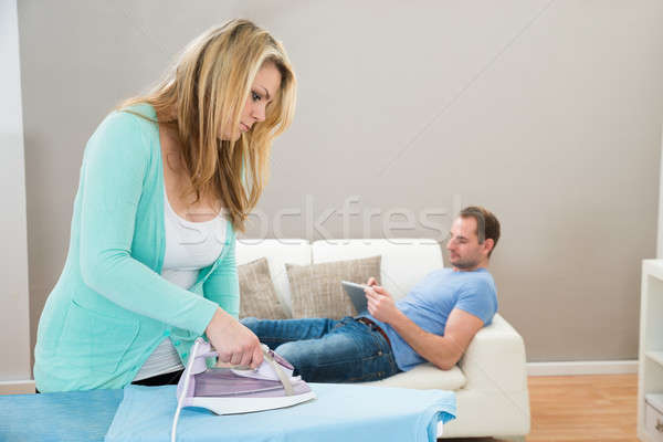 Woman Ironing Clothes While Man On Sofa Stock photo © AndreyPopov