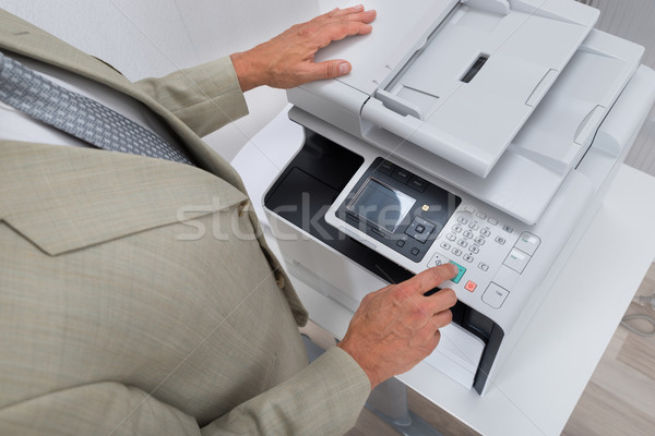 Businessman Pressing Printer's Button In Office Stock photo © AndreyPopov