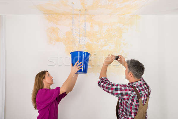 Man Photographing While Woman Collecting Water From Ceiling Stock photo © AndreyPopov