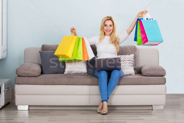 Woman Holding Shopping Bag With Laptop On Couch Stock photo © AndreyPopov