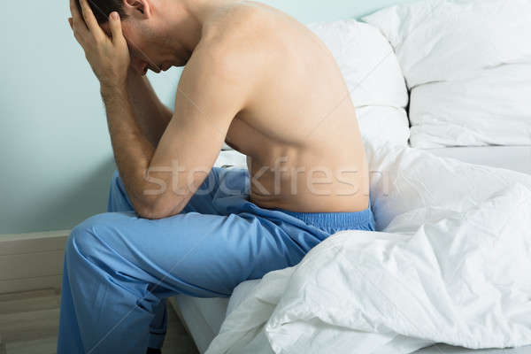 Hombre sufrimiento dolor de cabeza infeliz sesión cama Foto stock © AndreyPopov