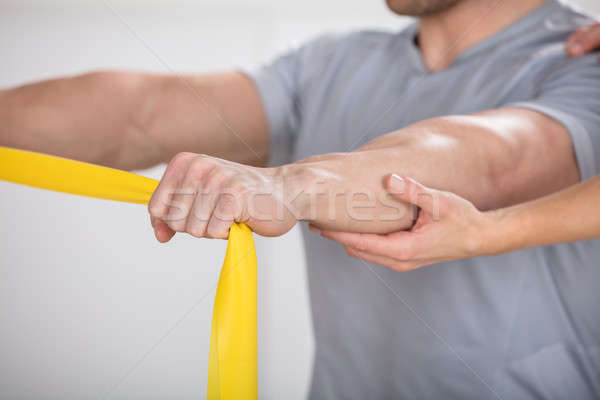 Physiotherapist Giving Man A Training With Exercise Band Stock photo © AndreyPopov