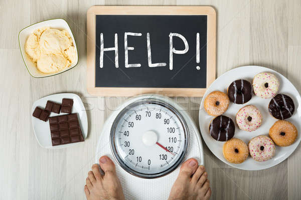 Stock photo: Man Measuring His Weight With Help Sign And Dessert