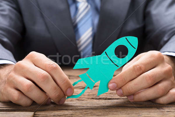 Businessman Holding Green Paper Rocket At Table Stock photo © AndreyPopov