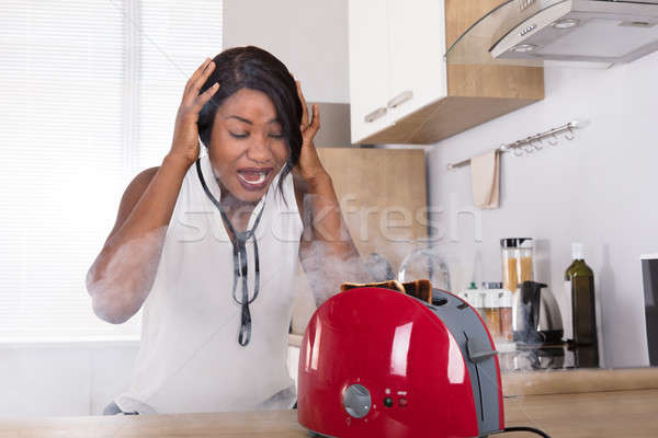 Frustrated Woman Looking At Burnt Toast Coming Out Of Toaster Stock photo © AndreyPopov