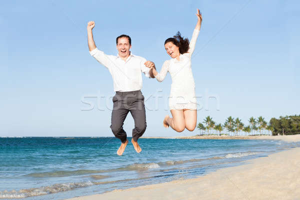 Excited Couple Holding Hands While Jumping At Beach Stock photo © AndreyPopov